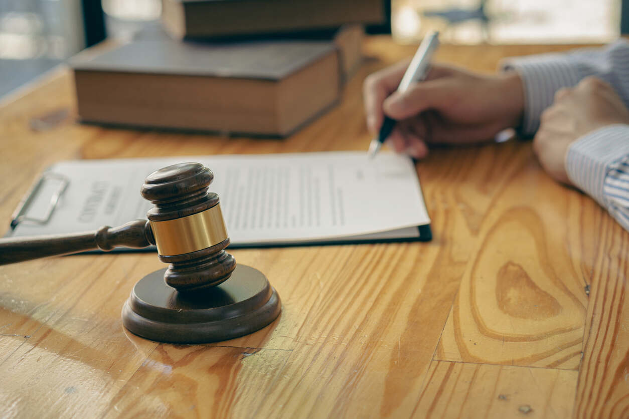 Lawyer signing documents with a gavel and legal books, symbolizing personal injury legal services.